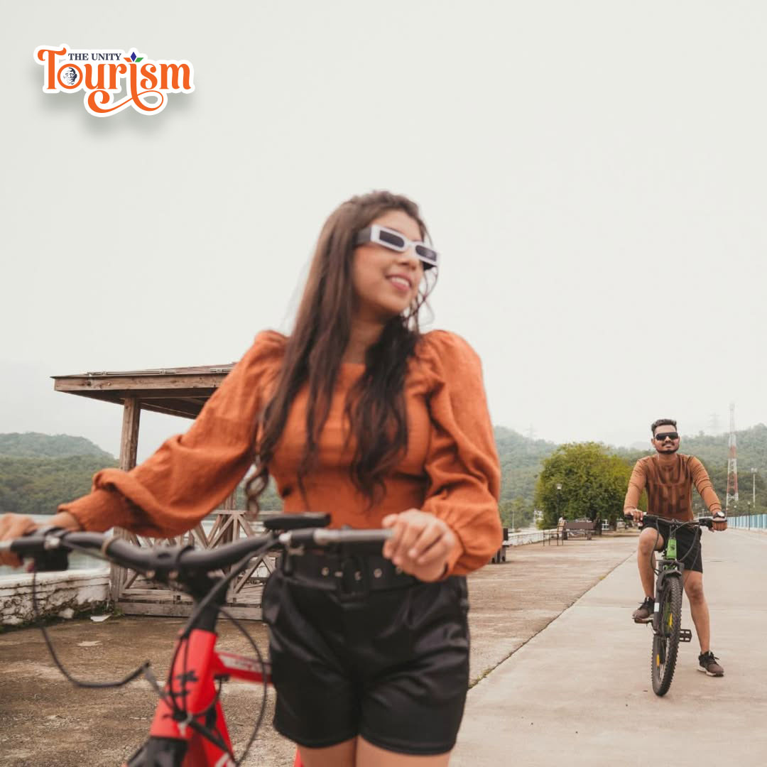 Riverfront cycling trail with a couple riding bicycles against a natural backdrop near Statue of Unity.